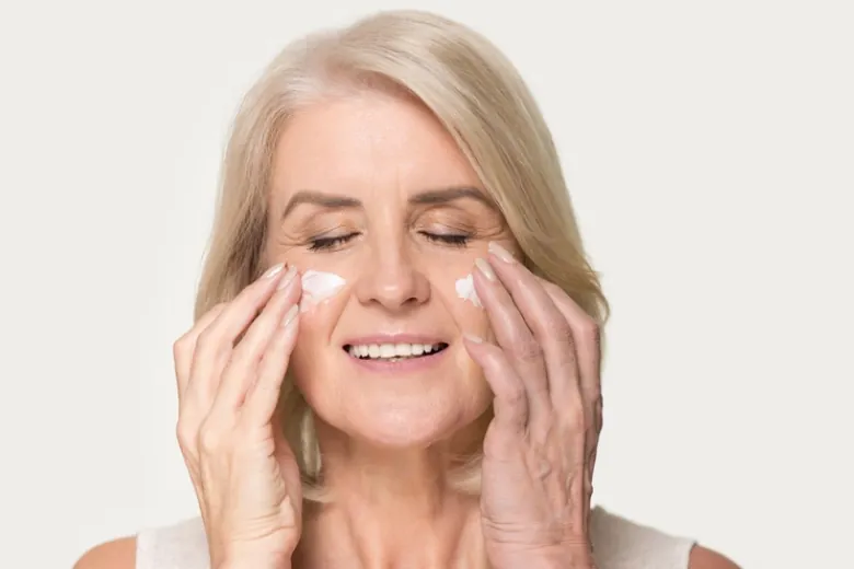 women putting cream on her face